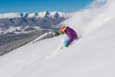 a person riding a snowboard down a snow covered slope at Red Hawk 2291 in Keystone