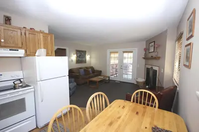 a kitchen and living room with a table and a white refrigerator at Streamside on Fall River in Estes Park