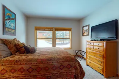 a bedroom with a bed and a flat screen tv at Snake River Village in Keystone