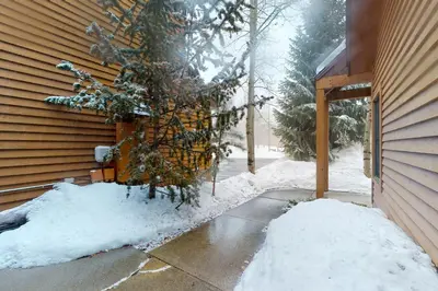 a tree is covered in snow next to a house at Snake River Village in Keystone