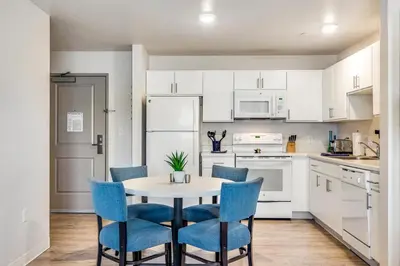 a kitchen with white cabinets and a table with blue chairs at Parks Residential Denver in Centennial
