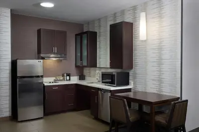 a kitchen with a table and a stainless steel refrigerator at Residence Inn by Marriott Denver Southwest/Littleton in Littleton
