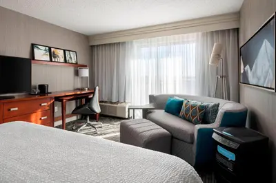 a hotel room with a bed and a chair and a desk at Courtyard by Marriott Denver Airport in Denver