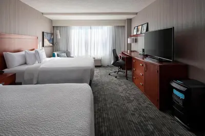 a hotel room with two beds and a flat screen tv at Courtyard by Marriott Denver Airport in Denver