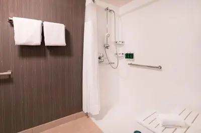 a bathroom with a shower and a toilet and towels at Courtyard by Marriott Denver Airport in Denver