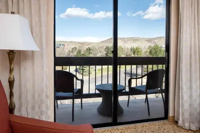 a room with a balcony with two chairs and a table at Denver Marriott West in Golden