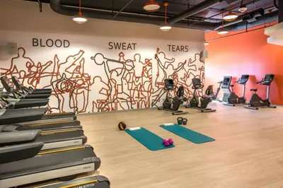 a gym with exercise equipment and a wall with a mural at Denver Marriott Tech Center in Greenwood Village