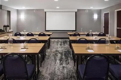 a classroom with tables and chairs and a projection screen at Courtyard by Marriott Fort Collins in Fort Collins
