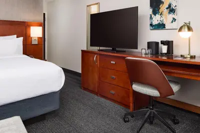 a hotel room with a bed and a desk with a television at Courtyard by Marriott Fort Collins in Fort Collins