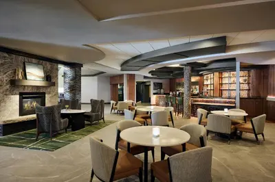 a restaurant with tables and chairs and a fireplace at Fort Collins Marriott in Fort Collins