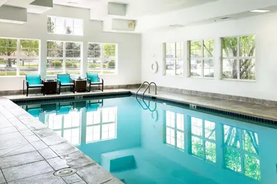 a swimming pool with blue chairs and windows at Residence Inn by Marriott Fort Collins in Fort Collins