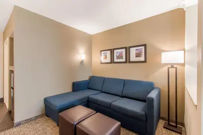 a living room with a blue couch and a stool at Comfort Suites Denver near Anschutz Medical Campus in Aurora