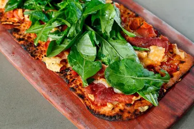 a pizza with greens on top of it on a plate at Boulder Marriott in Boulder