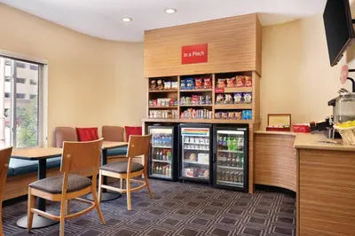 a restaurant with a refrigerator and tables and chairs at TownePlace Suites by Marriott Denver Downtown in Denver