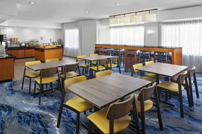 a restaurant with wooden tables and yellow chairs at Fairfield Inn & Suites Denver Airport in Denver