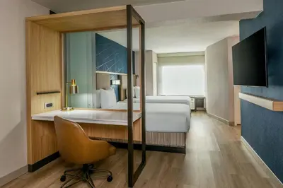 a bedroom with a bed and a chair and a mirror at SpringHill Suites Denver North / Westminster in Westminster