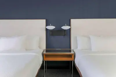 two beds with white sheets and a table between them at Courtyard by Marriott Denver Golden/Red Rocks in Golden
