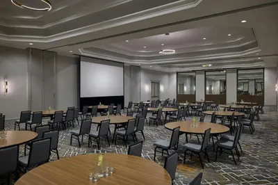 a conference room with tables and chairs and a projection screen at Denver Airport Marriott at Gateway Park in Aurora