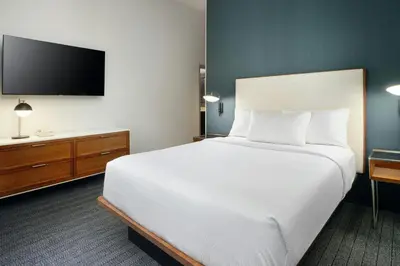 a hotel room with a large bed and a flat screen tv at Courtyard Boulder Longmont in Longmont
