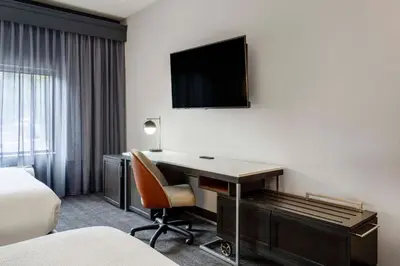 a hotel room with a desk and a tv on the wall at Courtyard by Marriott Denver Southwest Lakewood in Lakewood