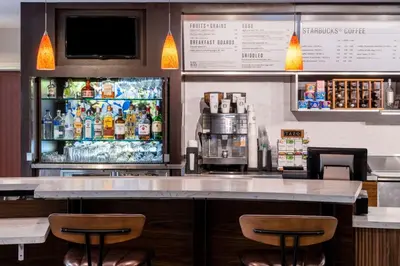 a bar with two stools in front of a refrigerator at Courtyard by Marriott Denver Southwest Lakewood in Lakewood