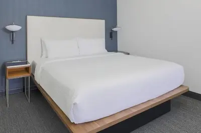 a bedroom with a large white bed and a night stand at Courtyard by Marriott Boulder Broomfield in Louisville