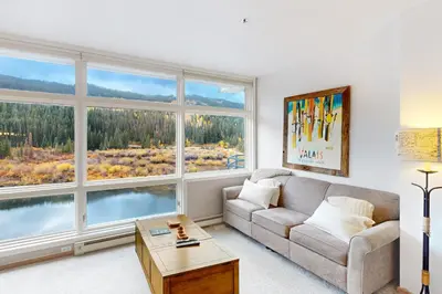 a living room with a couch and two large windows at River Bank Lodge 2924 in Keystone