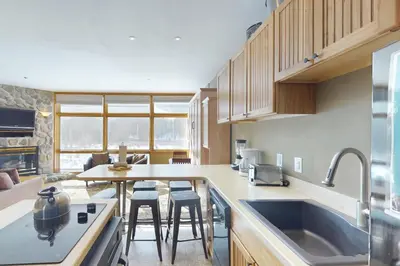 a kitchen with a sink and a table with stools at River Bank Lodge 2919 in Keystone