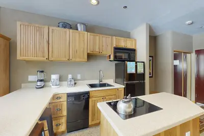 a kitchen with wooden cabinets and a black refrigerator at River Bank Lodge 2919 in Keystone