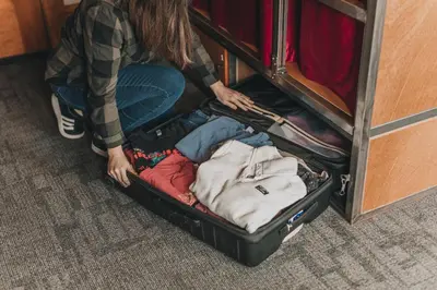 a woman is sitting in an open suitcase at Ember Hostel in Denver