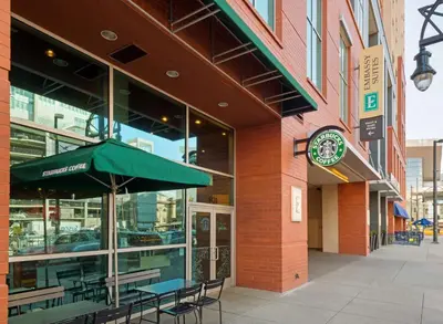 a building with a green umbrella and tables and chairs at Embassy Suites by Hilton Denver Downtown Convention Center in Denver