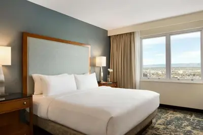 a large bed in a hotel room with a large window at Embassy Suites by Hilton Denver Downtown Convention Center in Denver
