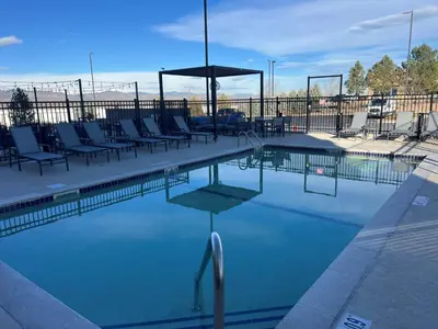 a large swimming pool with chairs and an umbrella at Staybridge Suites Denver South - Highlands Ranch by IHG in Littleton
