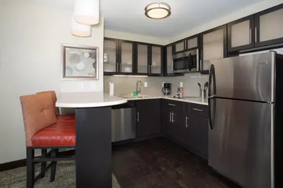 a kitchen with a refrigerator and a red chair at Staybridge Suites Denver South - Highlands Ranch by IHG in Littleton