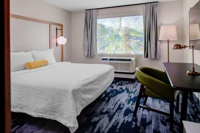 a hotel room with a bed and a desk and a window at Fairfield by Marriott Inn and Suites Boulder Broomfield Interlocken in Broomfield