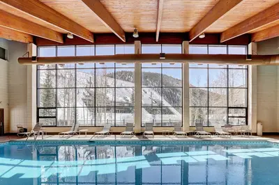 a large swimming pool with chairs and a large window at 2072 The Pines Condo in Keystone