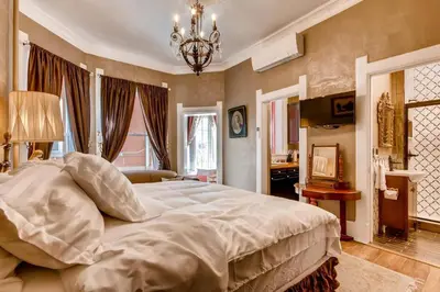 a bedroom with a large bed and a chandelier at The Holiday Chalet Victorian in Denver