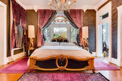 a bedroom with a large bed with a chandelier at The Holiday Chalet Victorian in Denver