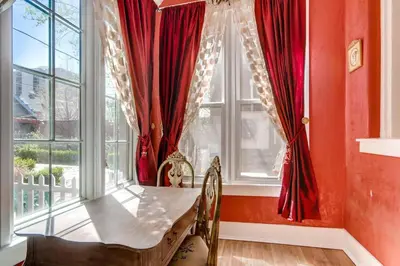 a room with red curtains and a table and a window at The Holiday Chalet Victorian in Denver