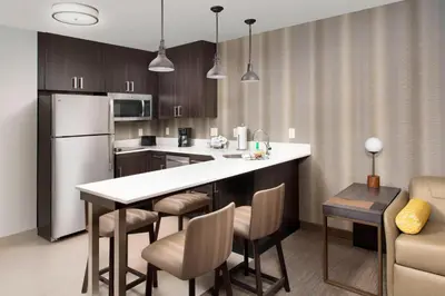 a kitchen with a kitchen island with chairs and a refrigerator at Residence Inn by Marriott Denver Airport/Convention Center in Denver