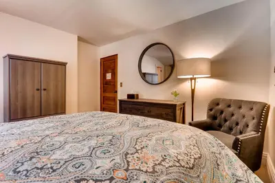 a bedroom with a bed and a chair and a mirror at Ski Tip Lodge, A Vail Resorts Property in Keystone