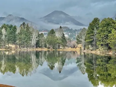 a lake with trees and a mountain in the background at Gateway to the Wildside Townhouse in Estes Park