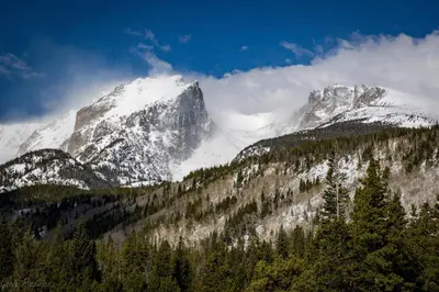 a snow covered mountain with trees in front of it at Gateway to the Wildside Townhouse in Estes Park