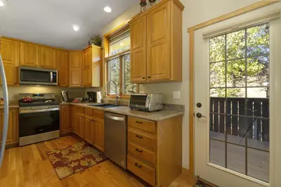 a kitchen with wooden cabinets and stainless steel appliances at Gateway to the Wildside Townhouse in Estes Park