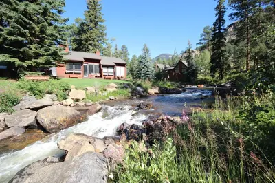a river in front of a house next to a house at Boulder Brook on Fall River in Estes Park