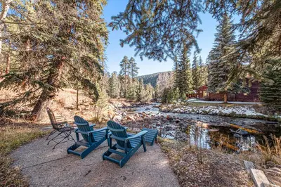 a group of chairs sitting next to a river at Boulder Brook on Fall River in Estes Park