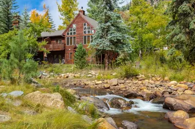 a house with a river in front of it at Boulder Brook on Fall River in Estes Park