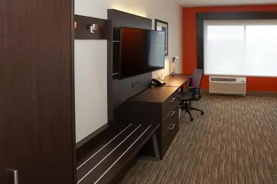 a hotel room with a flat screen tv and a desk at Holiday Inn Express & Suites - Aurora Medical Campus by IHG in Aurora