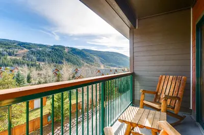 a balcony with a wooden chair and a view of the mountains at Gateway 5039 in Keystone