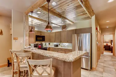 a kitchen with a counter with chairs and a refrigerator at Chateaux DuMont 2724 in Keystone